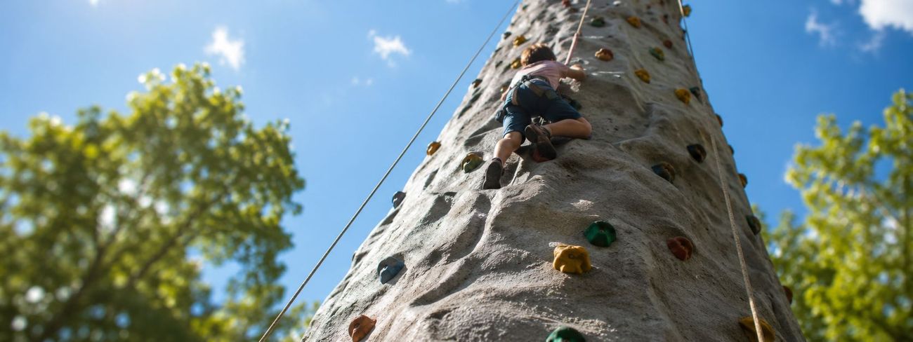 Looking up the side of a 26ft mobile climbing wall against a blue sky