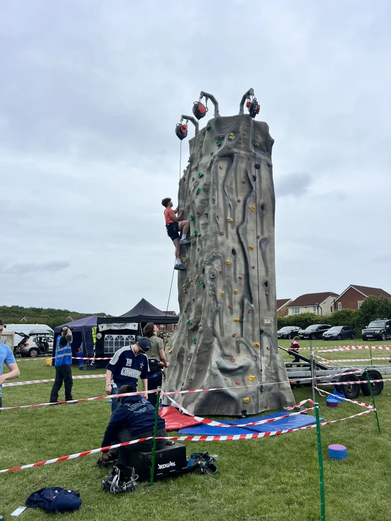 Child climbing the Enterprise mobile climbing wall on grass with safety mats and barriers