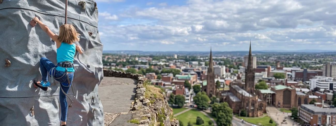 A climber on our mobile climbing wall high above Coventry