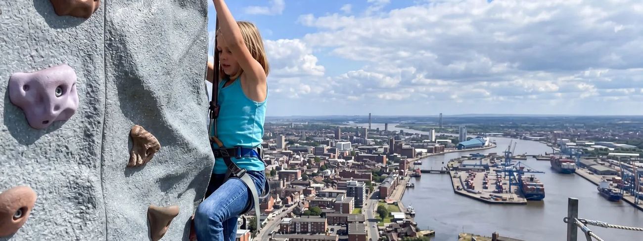 A climber on our mobile climbing wall high above Hull