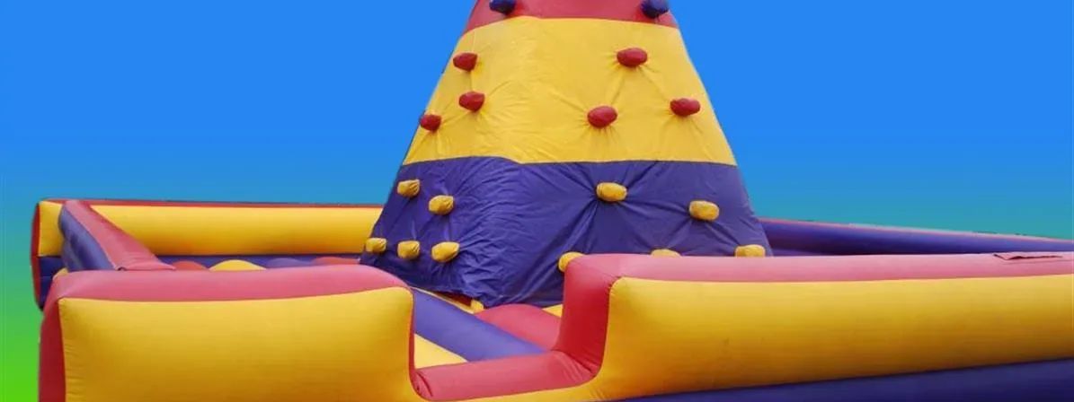 Colourful inflatable climbing wall with cone-shaped tower and padded safety base