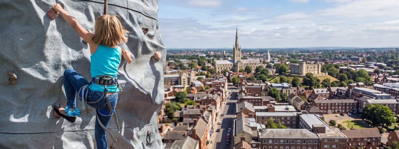 A climber on our mobile climbing wall high above Norwich