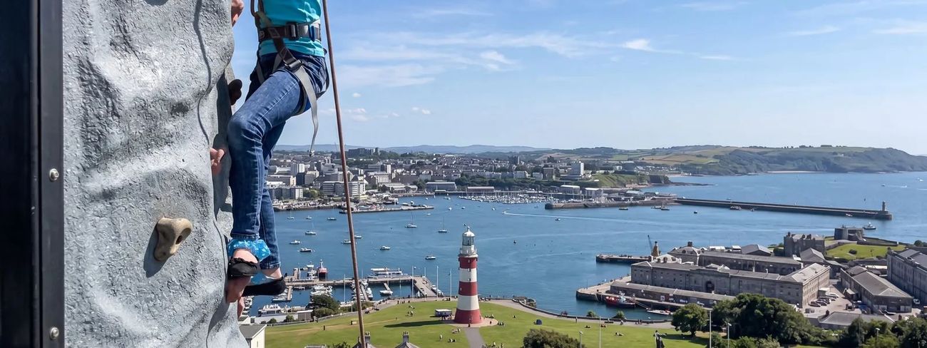 A climber on our mobile climbing wall high above Plymouth